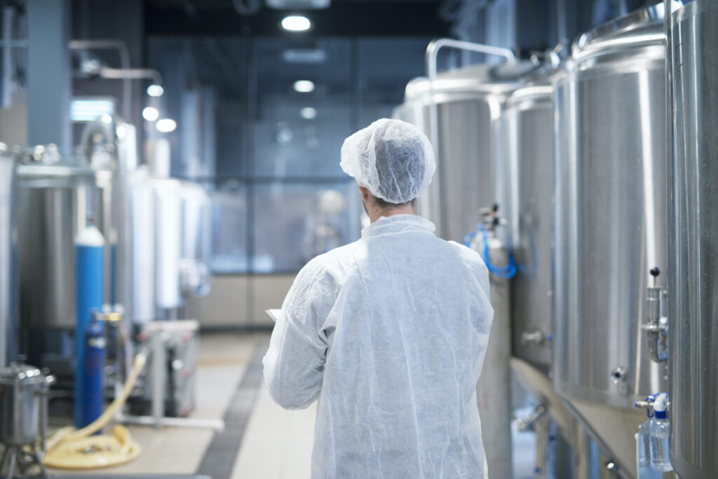 Technologist in a white protective suit walking through a food factory production line